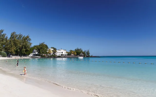 A white-sand beach with turquoise water and swimmers in the distance.