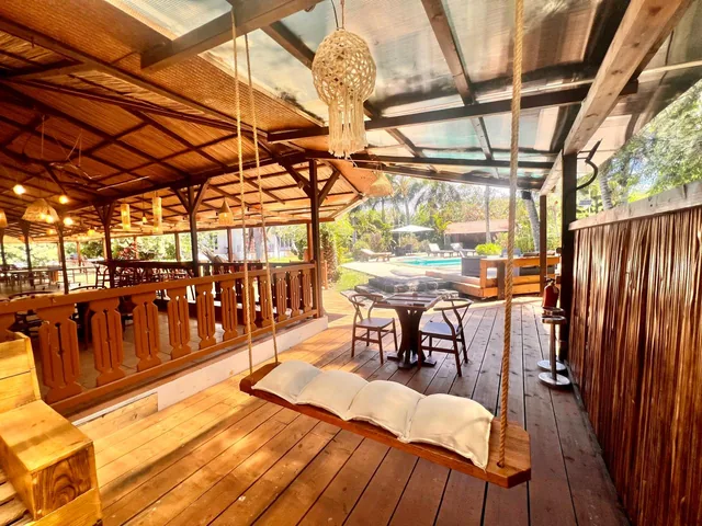 A hanging swing bench on the covered wooden deck, with the pool beyond.