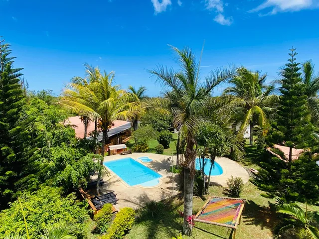 The tropical garden from above, with two pools, palm trees and hammock nets on the lawn.