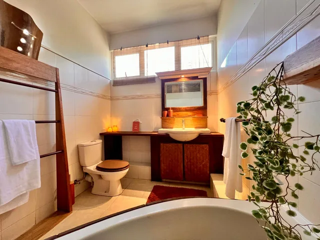 A lodge bathroom with a bathtub, a wooden vanity and a towel ladder.