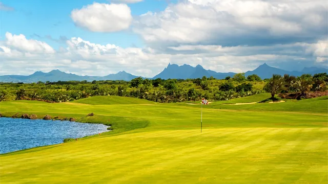 A golf course beside a lake, with mountains on the horizon.