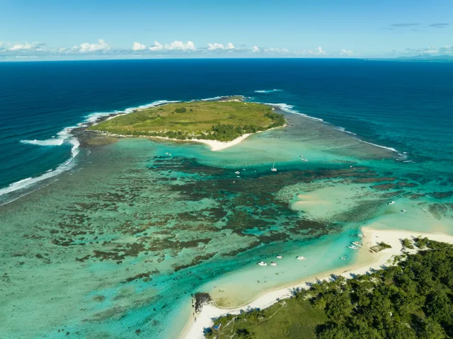 A small island ringed by reef and turquoise lagoon, seen from the air.