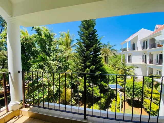 The balcony of a terrace lodge, looking out over palm trees and the garden.